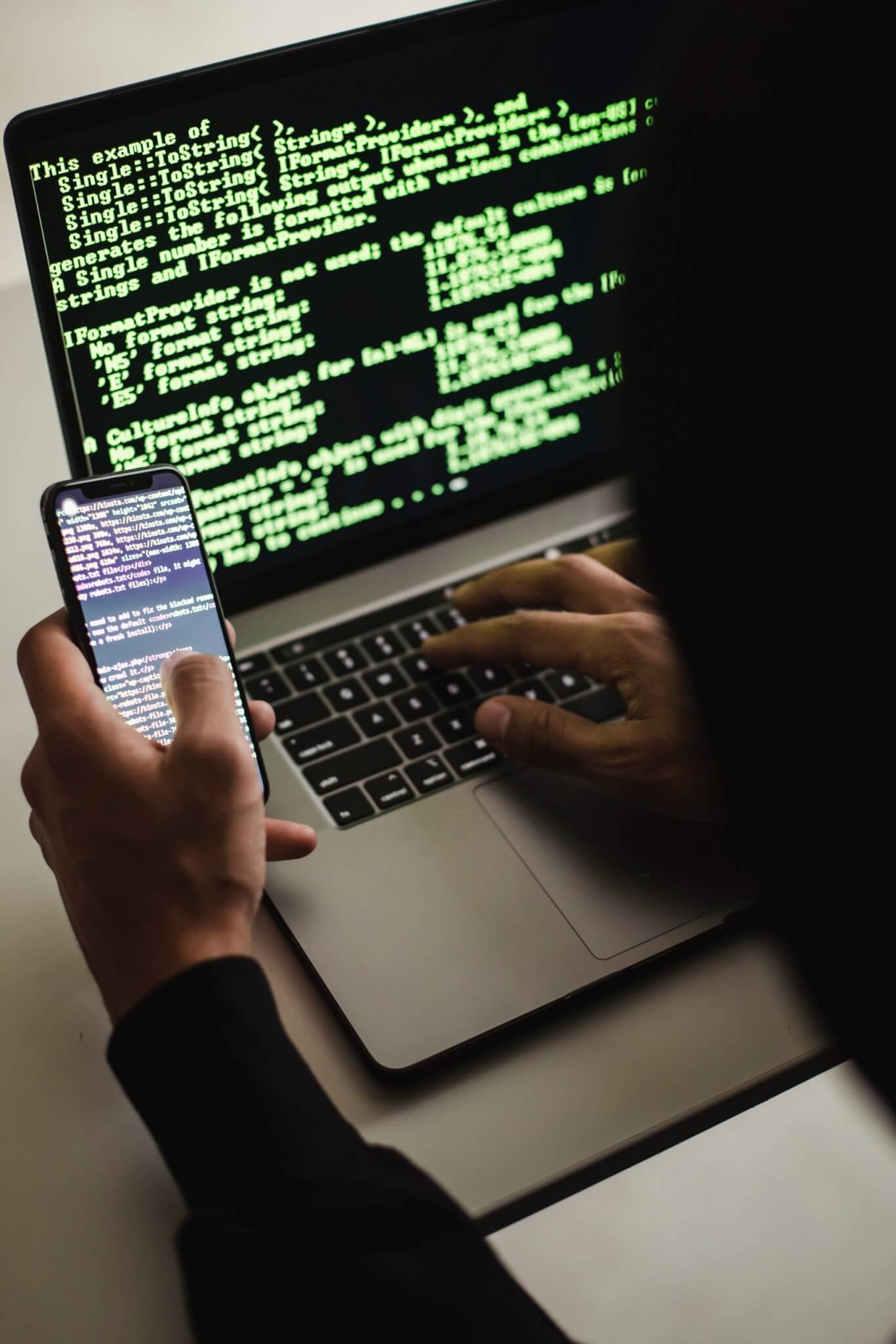 Free Unrecognizable hacker with smartphone typing on laptop at desk Stock Photo,Mobile Malware