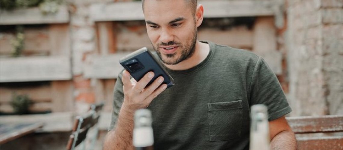 man in gray crew neck long sleeve shirt holding black smartphone
